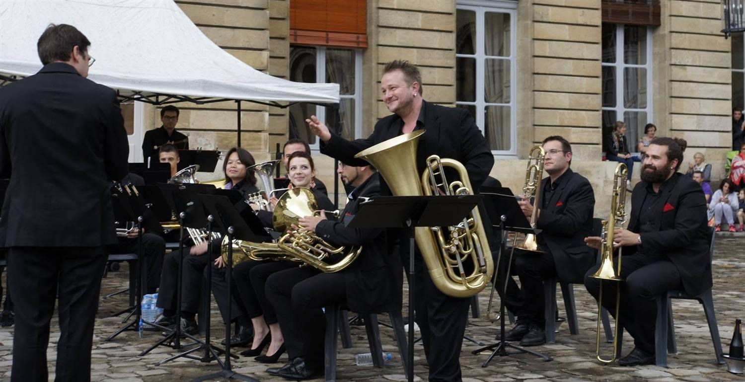 Le Brass Band Occitania jouant en extérieur devant un bâtiment bordelais.