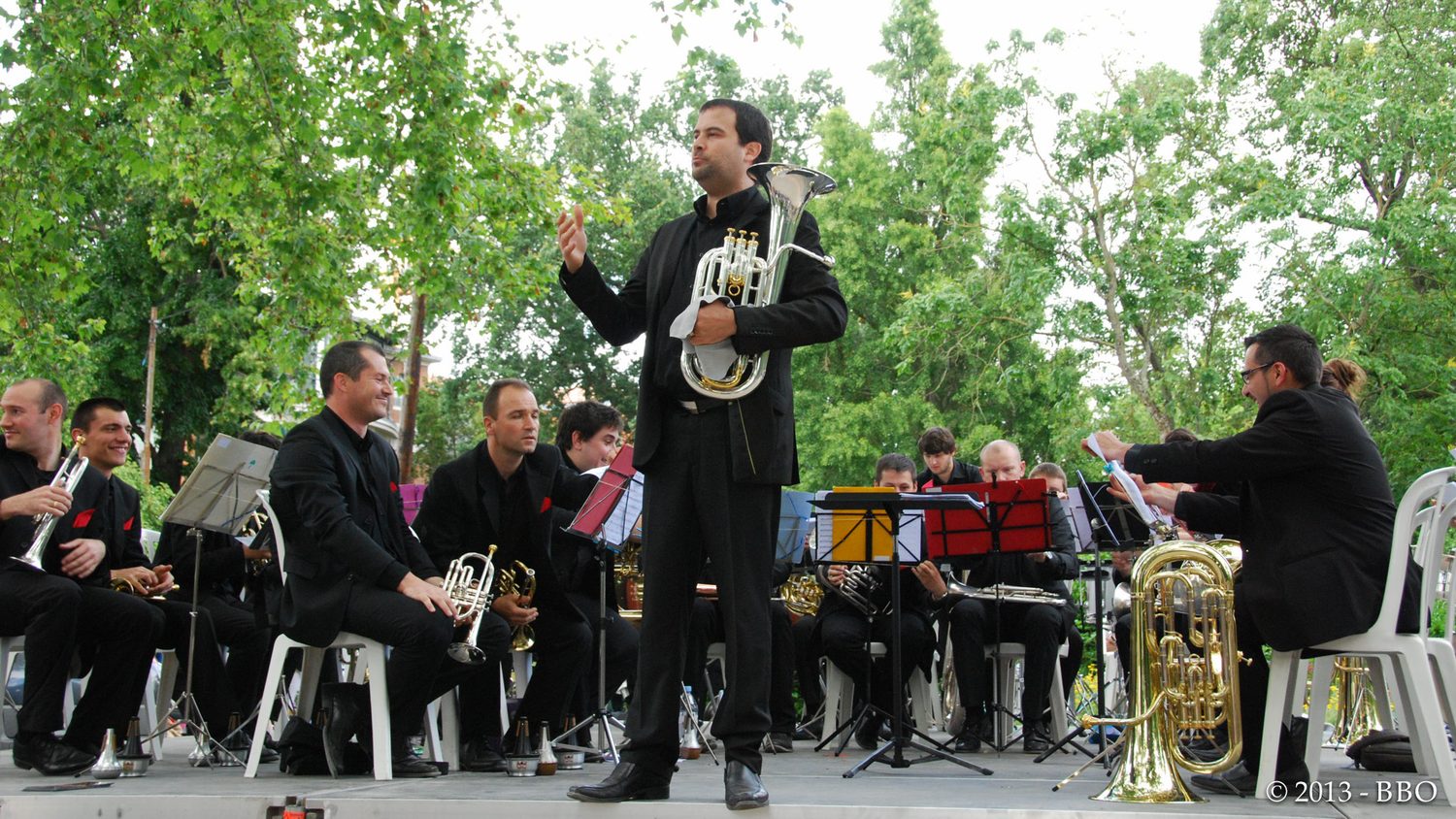 Pierre Baldassaré, euphonium sous le bras, s'adresse au public lors d'un concert du Brass Band Occitania au Jardin des Plantes de Toulouse.