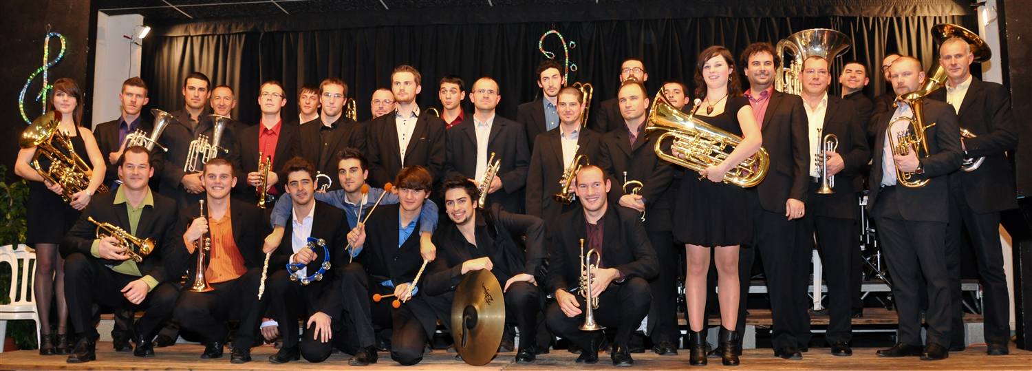 Le Brass Band Occitania sur scène devant un rideau rouge, lors de son tout premier concert.